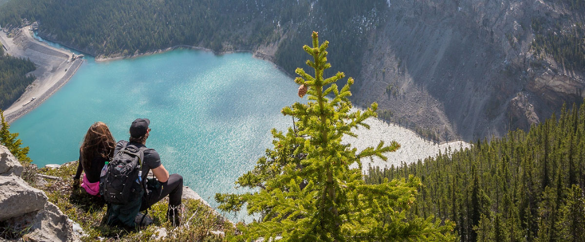 Man with the girl sitting by the lake on the mountain