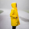 Girl in yellow coat standing on the middle on the road under rain