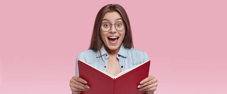 photo-intelligent-european-female-wonk-holds-opened-book-feels-happy-read-romantic-story-end-feels-excited-with-unexcpected-event-wears-jean-jacket-round-eyeglasses-stands-indoor