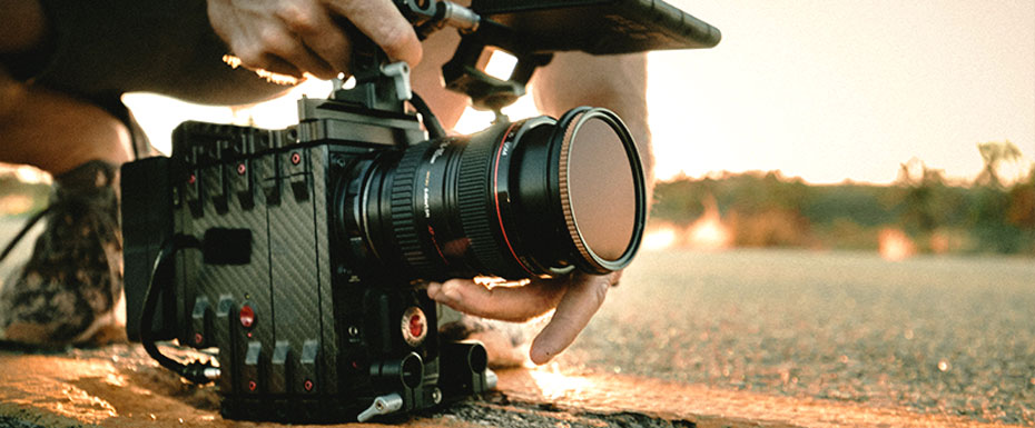 Guy Holding camera on the road during sunset