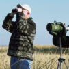 a group of men stand birdwatching