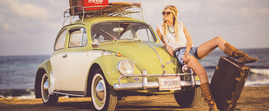 woman leaning on green and white Volkswagen Beetle near sea under white sky during daytime