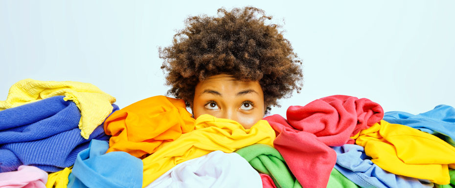 young afro-american woman surrounded by different colorful clothes sorts out wardrobe focused isolated white wall blank space your advertising content nothing wear concept