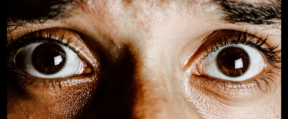 Crop face of person with brown eyes with fear on face looking at camera