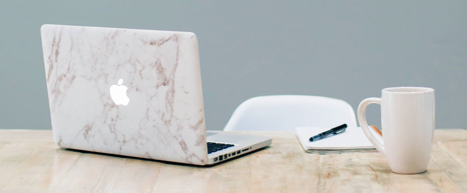 MacBook on table near mug