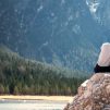 A couple sits on a rock looking out over a lake