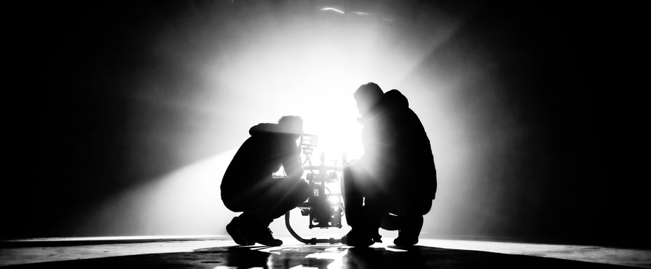 Grayscale photography of two crouching men making movie