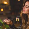 Woman holding fork in front table