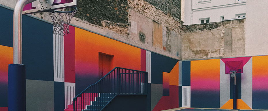 black, purple, and orange-basketball court beside concrete buildings at daytime