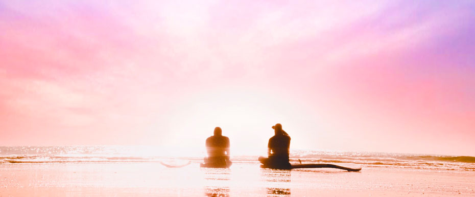 silhouette of two person sitting on seashore during dawn