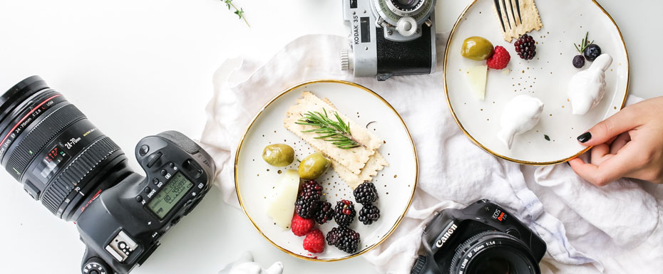 Three assorted cameras near fruits and ceramic Figurines