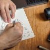 man writing on paper in front of DSLR