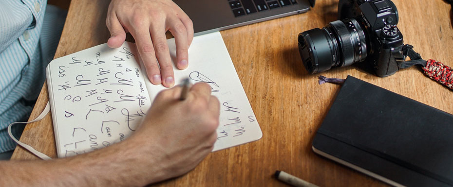 man writing on paper in front of DSLR