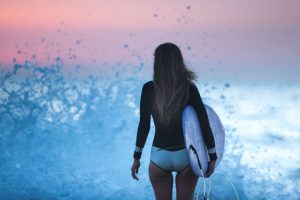 Woman in black long sleeve shirt and white shorts standing-on-blue Water during sunset